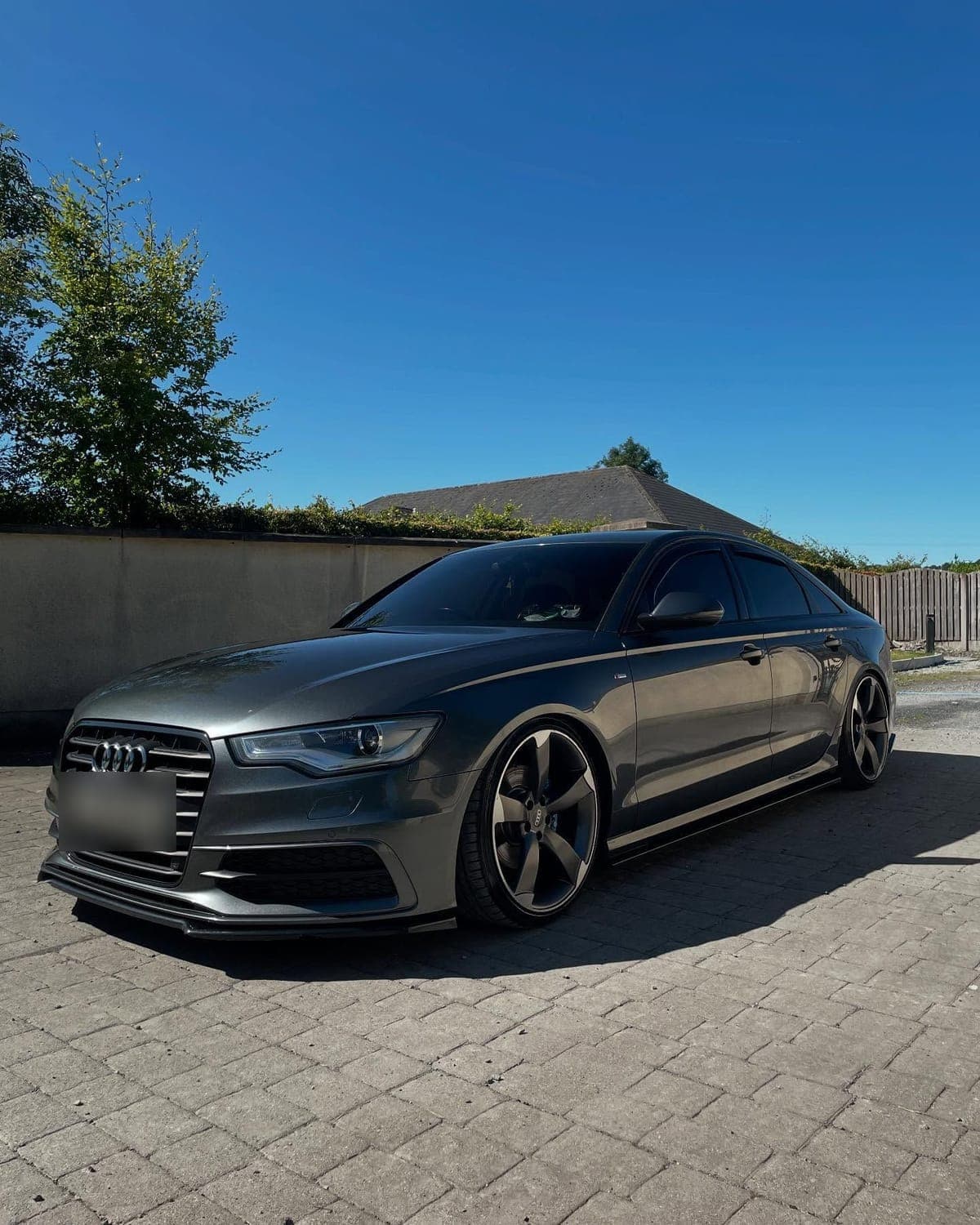 Grey Audi A6 with black alloy wheels under a clear blue sky after a clean