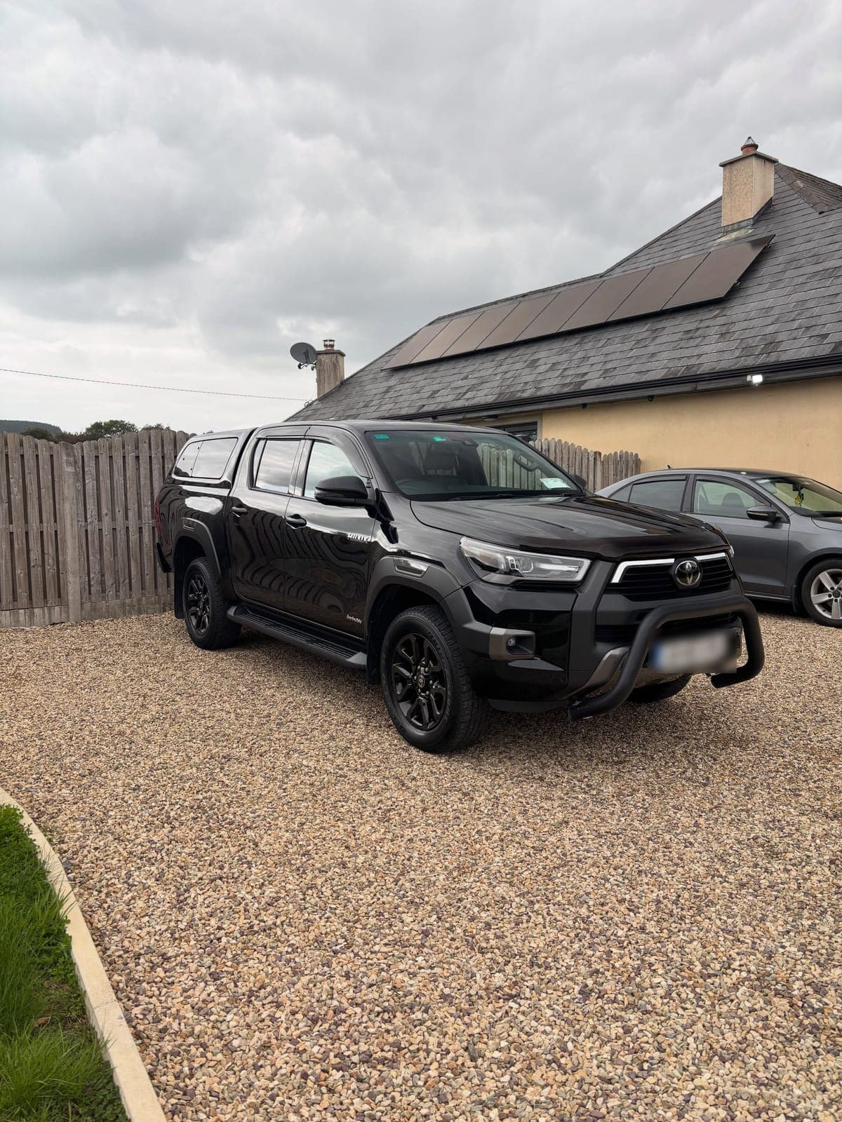 Black Toyota Hilux pickup on a gravel driveway after a clean